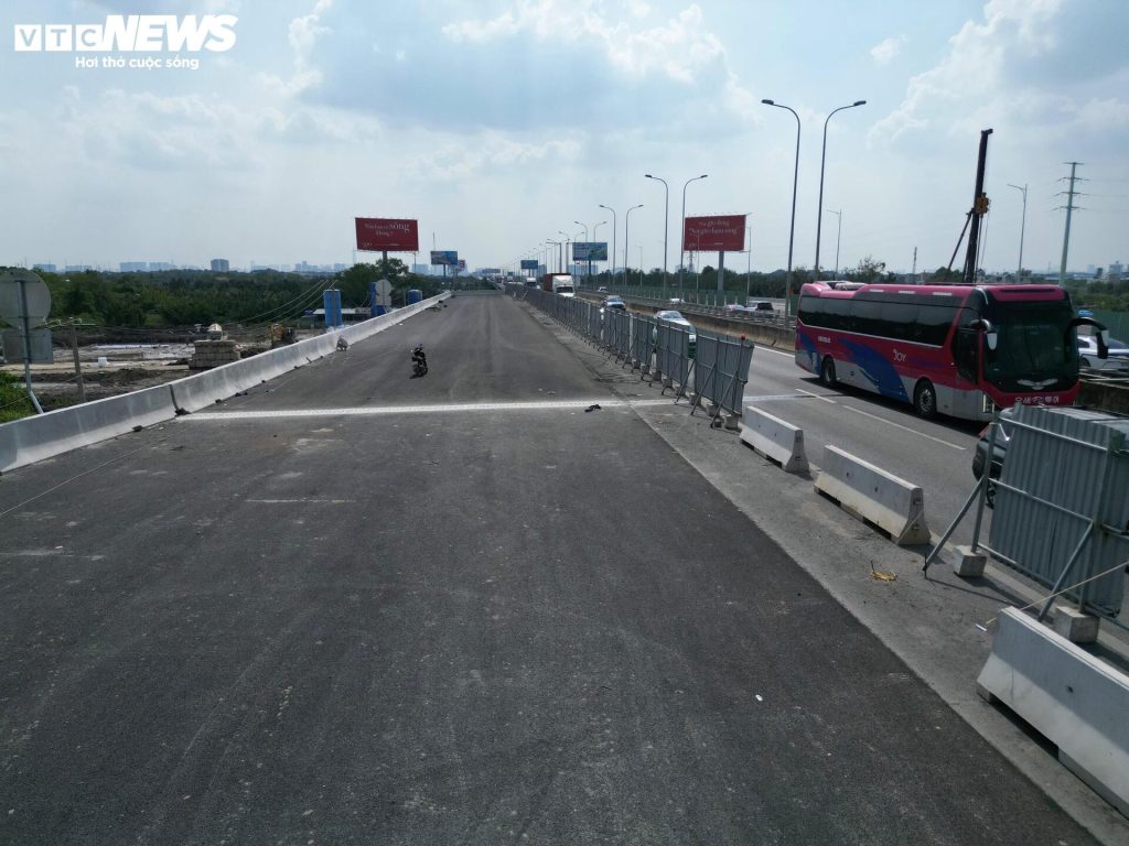 Tại nhánh kết nối từ đường dẫn Vành đai 3 lên cao tốc TP.HCM – Long Thành – Dầu Giây, mặt đường đã được thảm nhựa hoàn thiện, hệ thống dải phân cách cứng và rào tạm được bố trí để đảm bảo an toàn trong quá trình thi công.